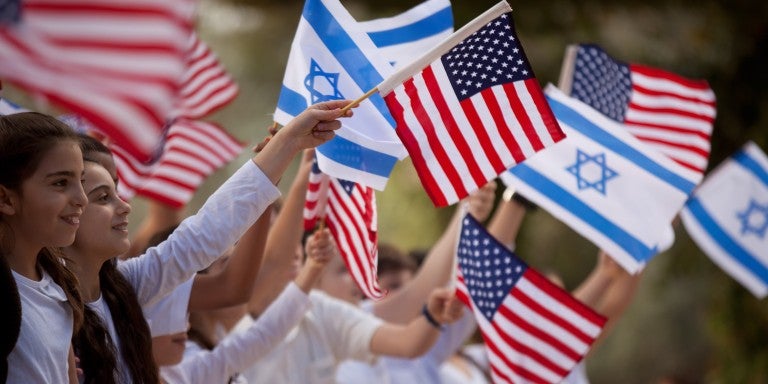 Children waving Israeli and American flags, smiling